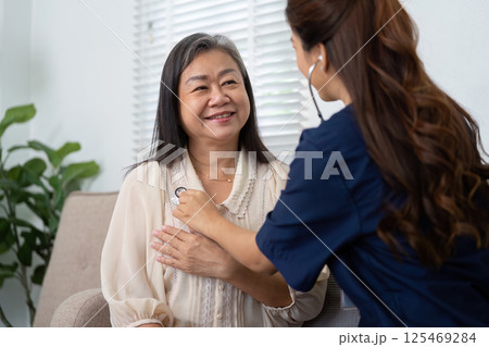 Caregiver and Elderly Interaction. A caregiver checks the heartbeat of an elderly patient, showcasing professional care and trust. Caregiver and Elderly Interaction. A caregiver checks the heartbeat of an elderly patient, showcasing professional care and trust. 125469284