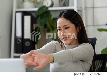 Wellness and Motivation. A woman stretches her arms while enjoying a productive work-from-home routine. Wellness and Motivation. A woman stretches her arms while enjoying a productive work-from-home routine. 125469286