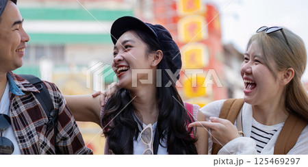 Close up of young Asian friends sharing laughter and joy while exploring a vibrant market, emphasizing travel and friendship. 125469297