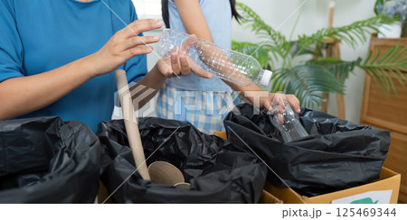 Sorting Waste and Environmental Education. An adult instructing a child on proper recycling methods. 125469344