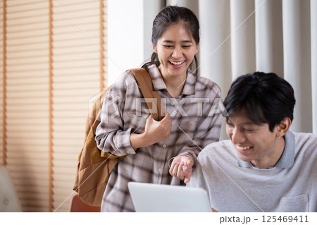 Joyful Learning and Interaction. Two students happily collaborating on a laptop, showcasing their enthusiasm for studying. 125469411