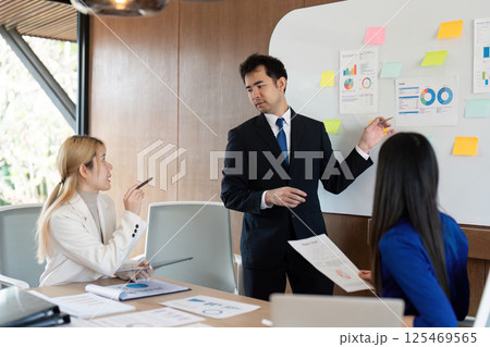 Diverse business team engaging in strategic discussions, presenting financial data in a modern workspace. 125469565