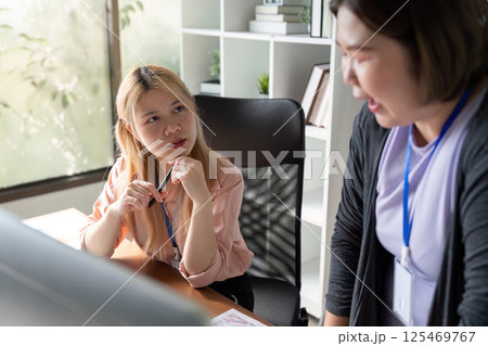 Graphic design team engaged in a thoughtful discussion in a modern office setting. 125469767