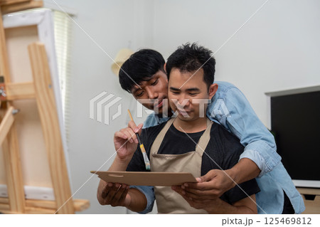 Couple and Artistry. A loving gay couple engages in a creative painting session together, sharing laughter and affection. 125469812
