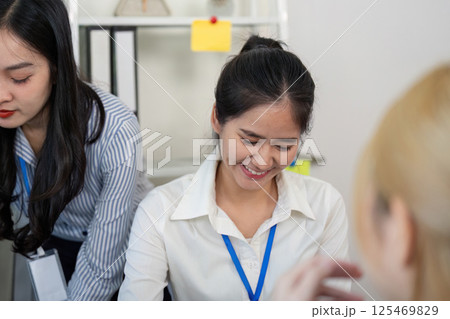 Two female professionals exchanging ideas and smiles during a collaborative meeting in a contemporary office Two female professionals exchanging ideas and smiles during a collaborative meeting in a contemporary office 125469829
