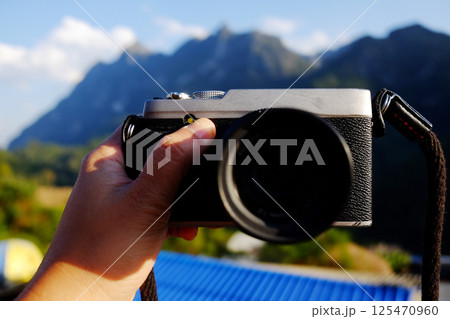 Hand holding vintage mirrorless camera with blue sky on valley Doi Luang Chiang Dao mountain view in Chiang Mai Province of Thailand Hand holding vintage mirrorless camera with blue sky on valley Doi Luang Chiang Dao mountain view in Chiang Mai Province of Thailand 125470960
