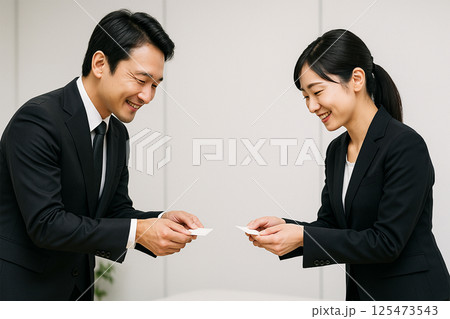笑顔で名刺を交換する日本人男女のビジネスマナー 125473543