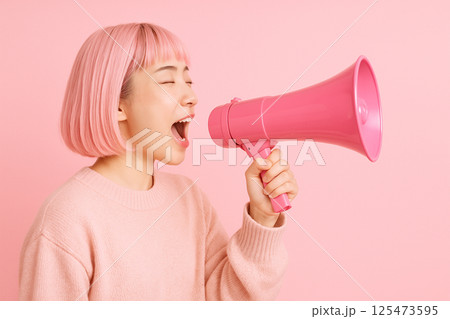 ピンクの世界でメガホンを使って叫ぶ若い日本人女性 125473595