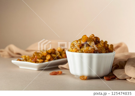 Yellow sultana raisins in a white bowl. 125474835