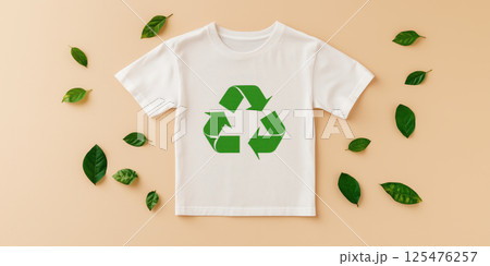 White t shirt with green recycle symbol surrounded by green leaves on beige background 125476257