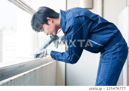 外装工事でコーキング材を塗る作業員の男性 125476777