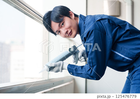 外装工事でコーキング材を塗る作業員の男性 125476779