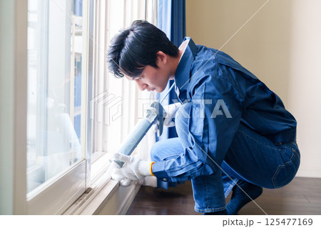 窓にコーキング材を塗る男性の作業員 窓にコーキング材を塗る男性の作業員 125477169