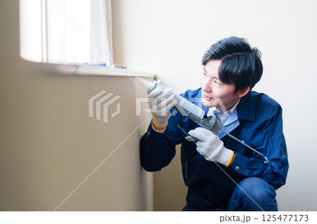 窓にコーキング材を塗る男性の作業員 窓にコーキング材を塗る男性の作業員 125477173