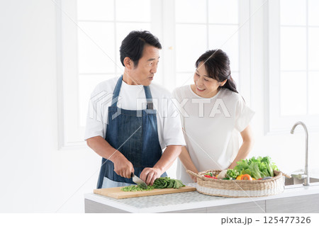 料理をする夫と見守る妻 料理をする夫と見守る妻 125477326