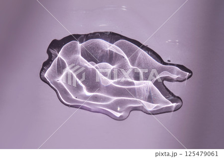 A drop of oil serum on a purple background with beautiful highlights. A drop of oil serum on a purple background with beautiful highlights. 125479061