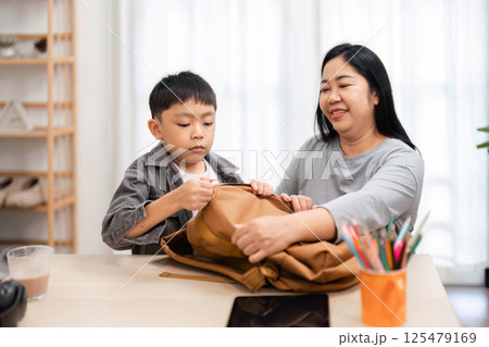 Back to School and Preparation. A mother helping her son pack his backpack for school. Back to School and Preparation. A mother helping her son pack his backpack for school. 125479169