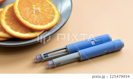 Two Insulin injection pen for diabetics and weight loss and plate with orange Two Insulin injection pen for diabetics and weight loss and plate with orange 125479934