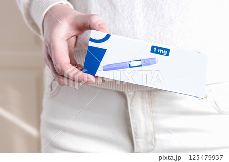 Woman in white clothes holding a pack of Ozempic Insulin injection pen for diabetics and weight loss. 125479937