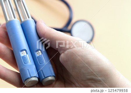 Women's hands holding Insulin injection pen for diabetics and weight loss. 125479938