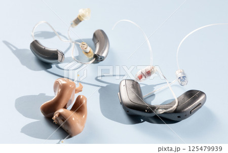 Various modern hearing aids on a blue background 125479939