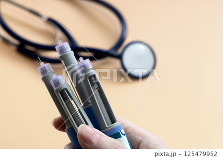 Women's hands holding Insulin injection pen for diabetics and weight loss. 125479952