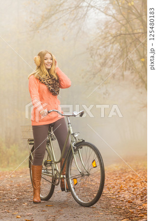 Happy active woman riding bike in autumn park. Happy active woman riding bike in autumn park. 125480183