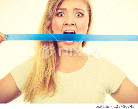Attractive blonde woman biting tape on mouth. 125480249