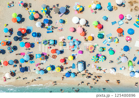 Aerial view of colorful umbrellas on beach, people in blue sea Aerial view of colorful umbrellas on beach, people in blue sea 125480896