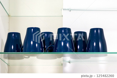 Ceramic cups on glass shelf 125482260