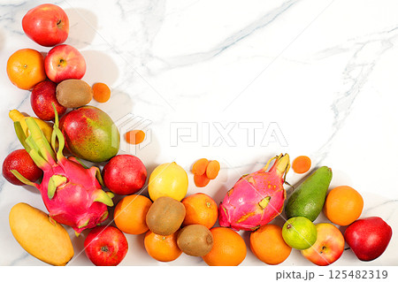 Healthy vegan food for weight loss. Banner with tropical exotic fruits and juice. Dragon fruit, pitaya, mango, kiwi, avacado, apples, citrus fruits and dried apricots on a sunny table. Healthy vegan food for weight loss. Banner with tropical exotic fruits and juice. Dragon fruit, pitaya, mango, kiwi, avacado, apples, citrus fruits and dried apricots on a sunny table. 125482319