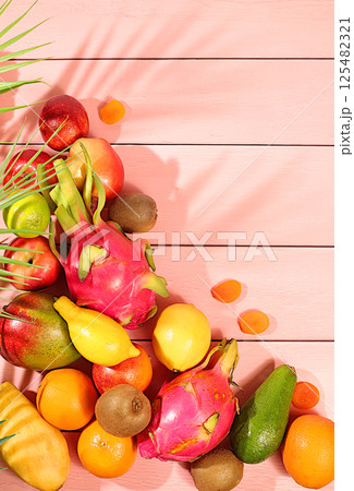 Healthy vegan food for weight loss. Banner with tropical exotic fruits and juice. Dragon fruit, pitaya, mango, kiwi, avacado, apples, citrus fruits and dried apricots on a sunny table. Healthy vegan food for weight loss. Banner with tropical exotic fruits and juice. Dragon fruit, pitaya, mango, kiwi, avacado, apples, citrus fruits and dried apricots on a sunny table. 125482321