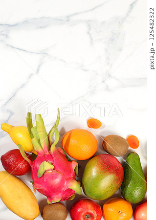 Dragon fruit, pitaya, mango, kiwi, avacado, apples, citrus and dried apricots on a sunny table with space for text. Healthy vegan food for weight loss. Banner with tropical exotic fruits and juice 125482322