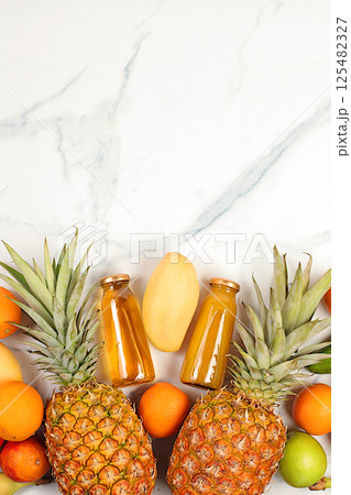 Summer tropical fruits and juices on marble table, source of vitamin C, banner for shop, healthy vegan products for healthy lifestyle, detox diet and weight loss concept, shop advertisement. 125482327
