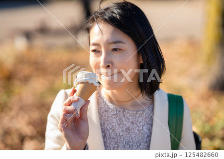 観光先でソフトクリームを食べるミドル女性 125482660