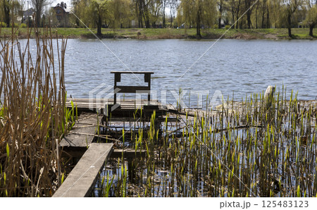 wooden pier and bench on the river on a spring day 125483123