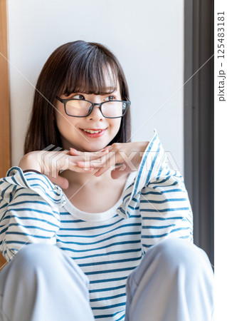 部屋でくつろぐ眼鏡の若い女性 125483181