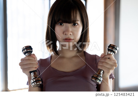 ダンベルでトレーニングする若い女性 125483421