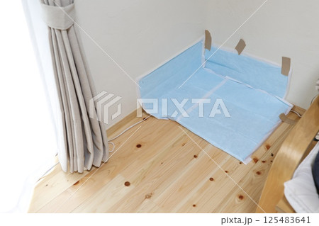 部屋の隅に敷かれた犬用ペットシーツは壁にガムテープで固定されている 125483641