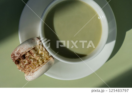 Nutrient-rich matcha drink with macaron dessert and trendy deep shadows on soft colored background. Morning beautiful breakfast present gift idea. Vibrant creative colors. Natural energy givers Nutrient-rich matcha drink with macaron dessert and trendy deep shadows on soft colored background. Morning beautiful breakfast present gift idea. Vibrant creative colors. Natural energy givers 125483797