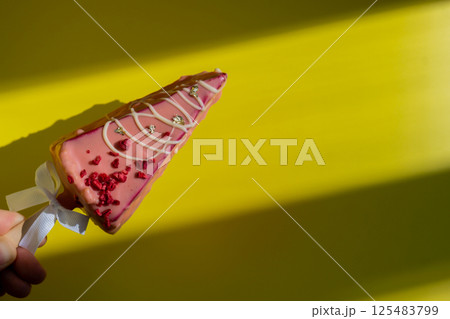 Female hand holding trendy sweet dessert cheesecake on colorful vibrant yellow background. Takeout takeaway present idea. Copy space for advertisement homemade cake bakery treat trend Female hand holding trendy sweet dessert cheesecake on colorful vibrant yellow background. Takeout takeaway present idea. Copy space for advertisement homemade cake bakery treat trend 125483799