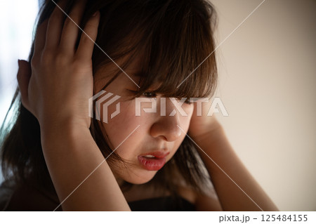 頭を抱えて悩む若い女性 頭を抱えて悩む若い女性 125484155
