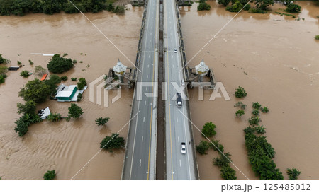Aerial view of car driving on the bridge while water rising during typhoon Yagi has swept Chiang Rai province of Thailand. 125485012