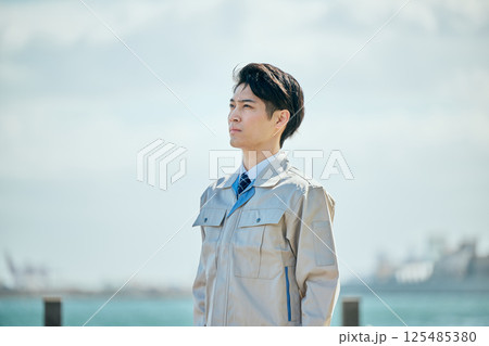 遠くを見つめる作業着姿の20代の若い男性 125485380