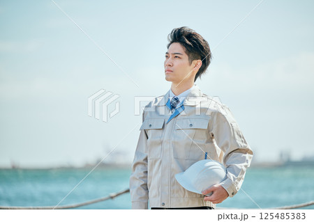 遠くを見つめる作業着姿の20代の若い男性 125485383