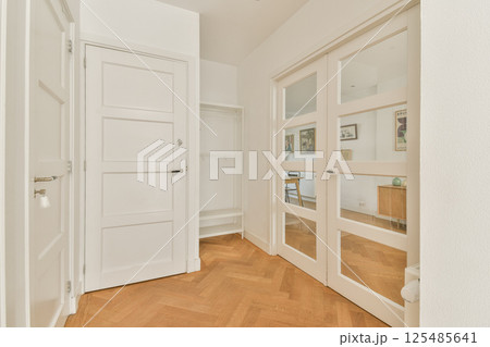A stylish entryway featuring white doors and herringbone wooden flooring, creating a bright and inviting atmosphere. A stylish entryway featuring white doors and herringbone wooden flooring, creating a bright and inviting atmosphere. 125485641