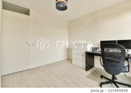 A clean and minimalistic office interior featuring a desk, chair, and neutral wall colors. Perfect for a workspace aesthetic. 125485649