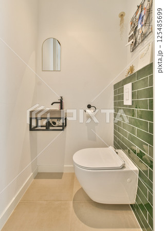 A sleek bathroom featuring a modern toilet and a stylish green tile accent wall. The minimalist design provides a clean and refreshing aesthetic. A sleek bathroom featuring a modern toilet and a stylish green tile accent wall. The minimalist design provides a clean and refreshing aesthetic. 125485699
