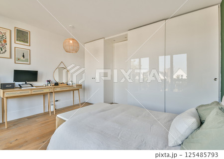 A beautifully arranged modern bedroom featuring a cozy bed, stylish furniture, and elegant decor, creating a serene atmosphere for relaxation. 125485793
