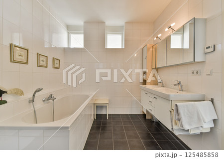 A sleek and contemporary bathroom featuring a bathtub, dual sinks, and stylish mirrors with natural light filtering through the windows, creating a serene ambiance. A sleek and contemporary bathroom featuring a bathtub, dual sinks, and stylish mirrors with natural light filtering through the windows, creating a serene ambiance. 125485858